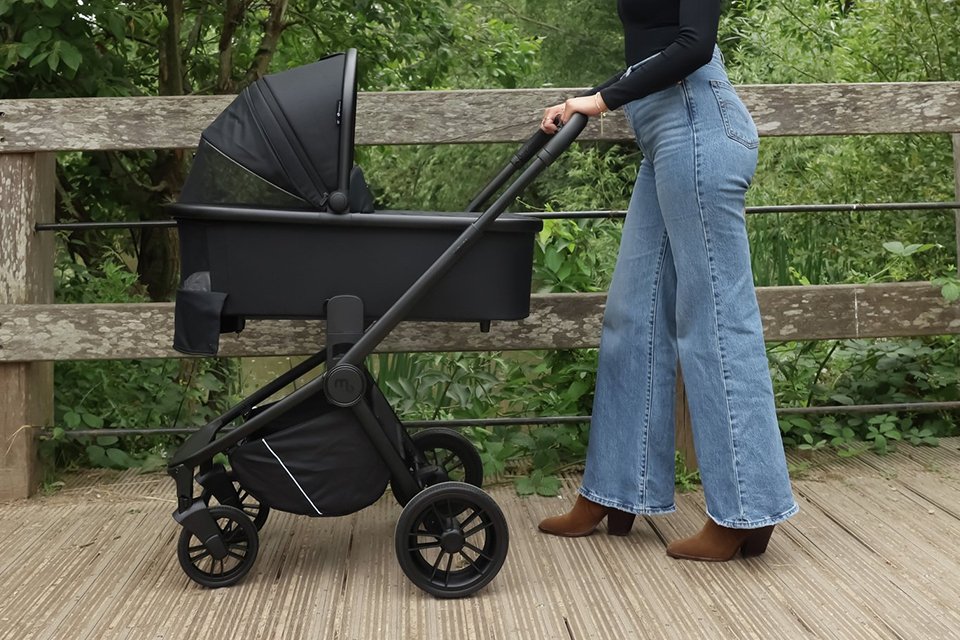 A mother pushing a My Babiie MB450I Travel System - Black.