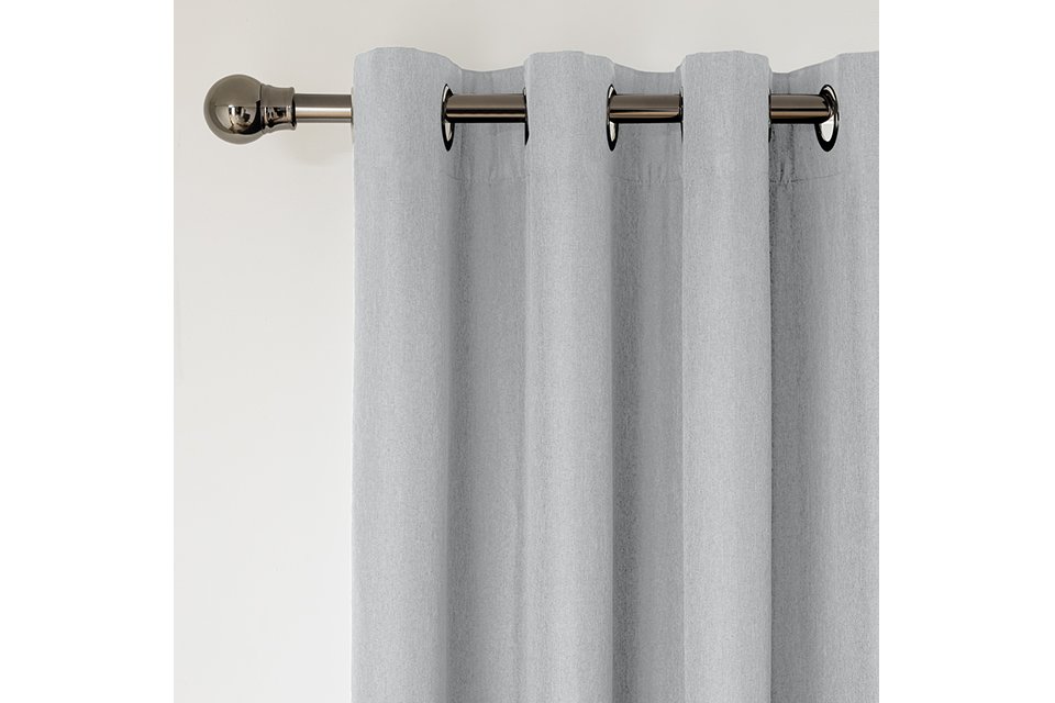 A grey curtain on a silver iron finish curtain pole.