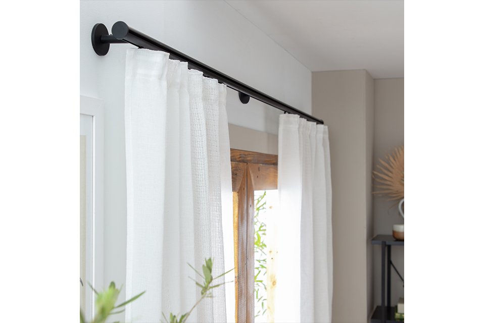 A white curtain on a black curtain track.