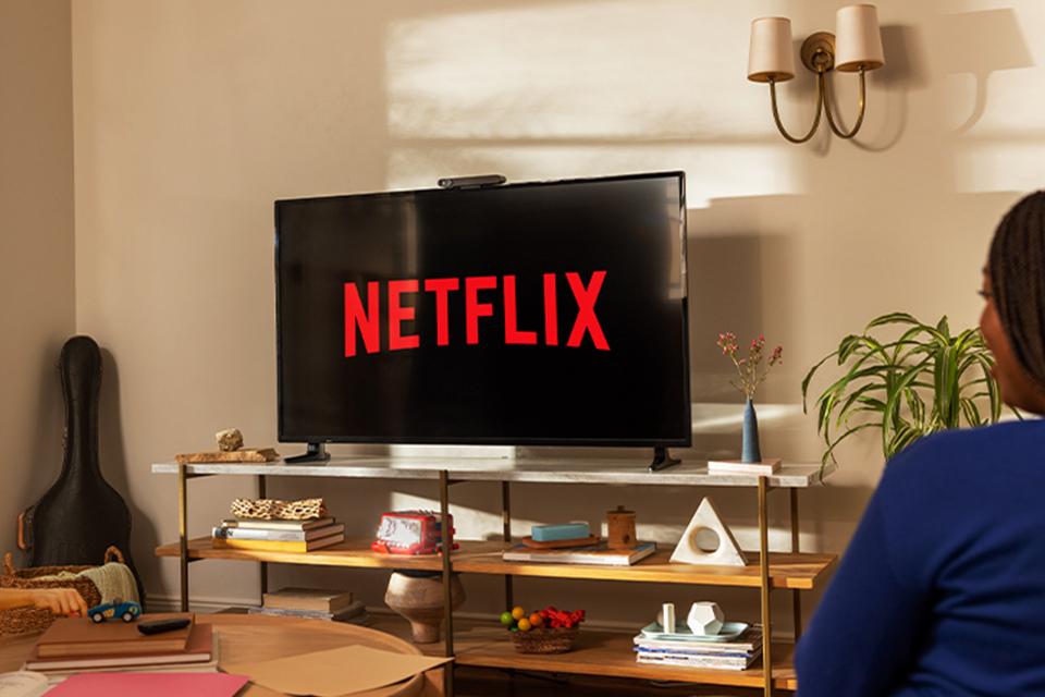 A TV screen displays the Netflix logo in a cosy living room.