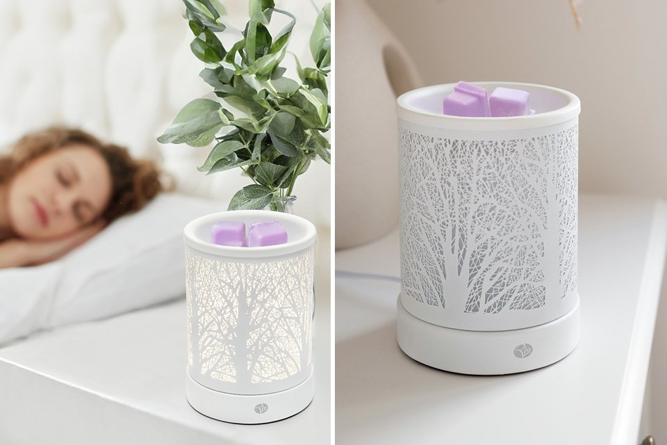 An electric diffuser on a table near a bed.