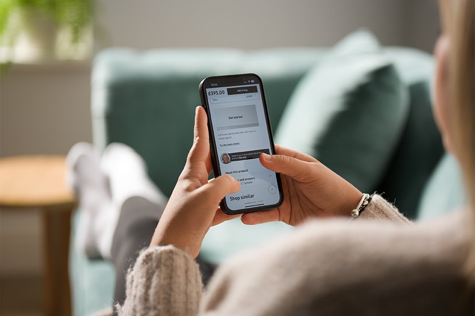 A women lying on a green sofa with her phone in hand.
