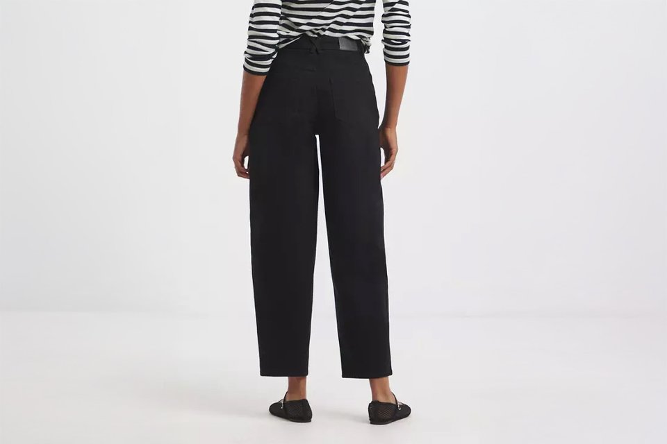 Person wearing a black-and-white striped long-sleeve top paired with high-waisted black straight-leg jeans and black flat shoes.