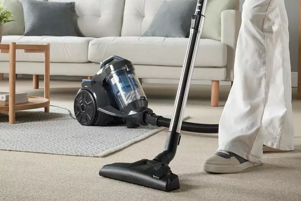 A person using a Bush Bagless Cylinder Pet Corded Vacuum Cleaner.