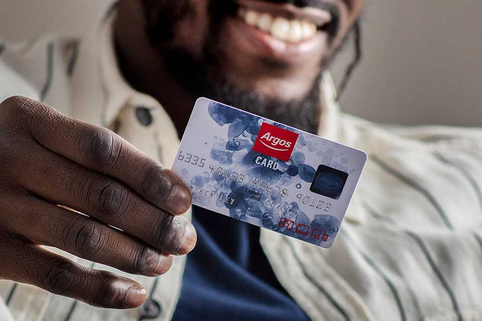 An image of a man smiling while holding his Argos Card.