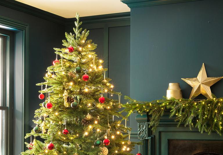 Image of a green living room with a Christmas tree deorated with gold, red and green baubles.