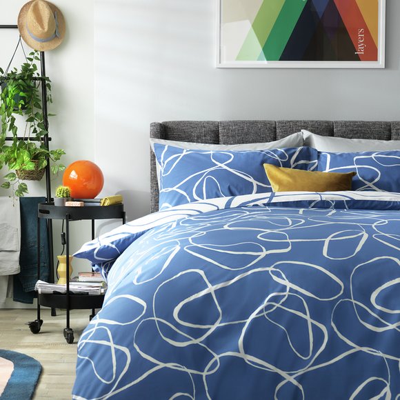 Blue reversible bedding on a grey bed frame.