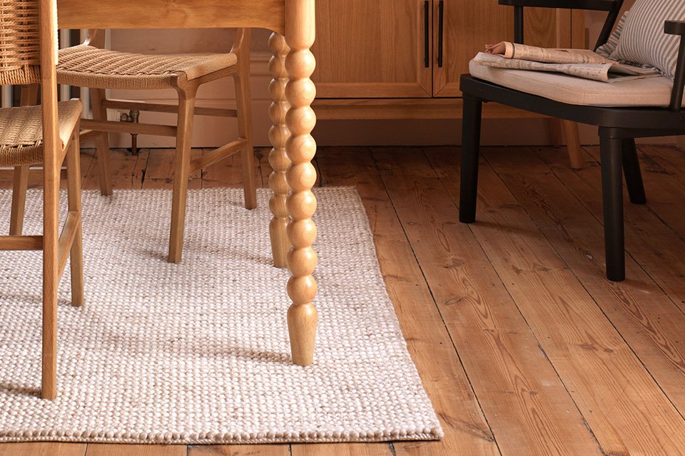 A white neutral piled rug under a dining table.