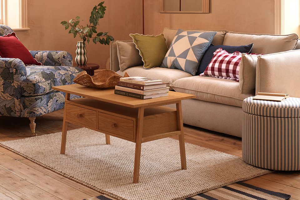 A living room with beige sofa, wooden finish coffee table, a natural finish rug and other home furnishings.