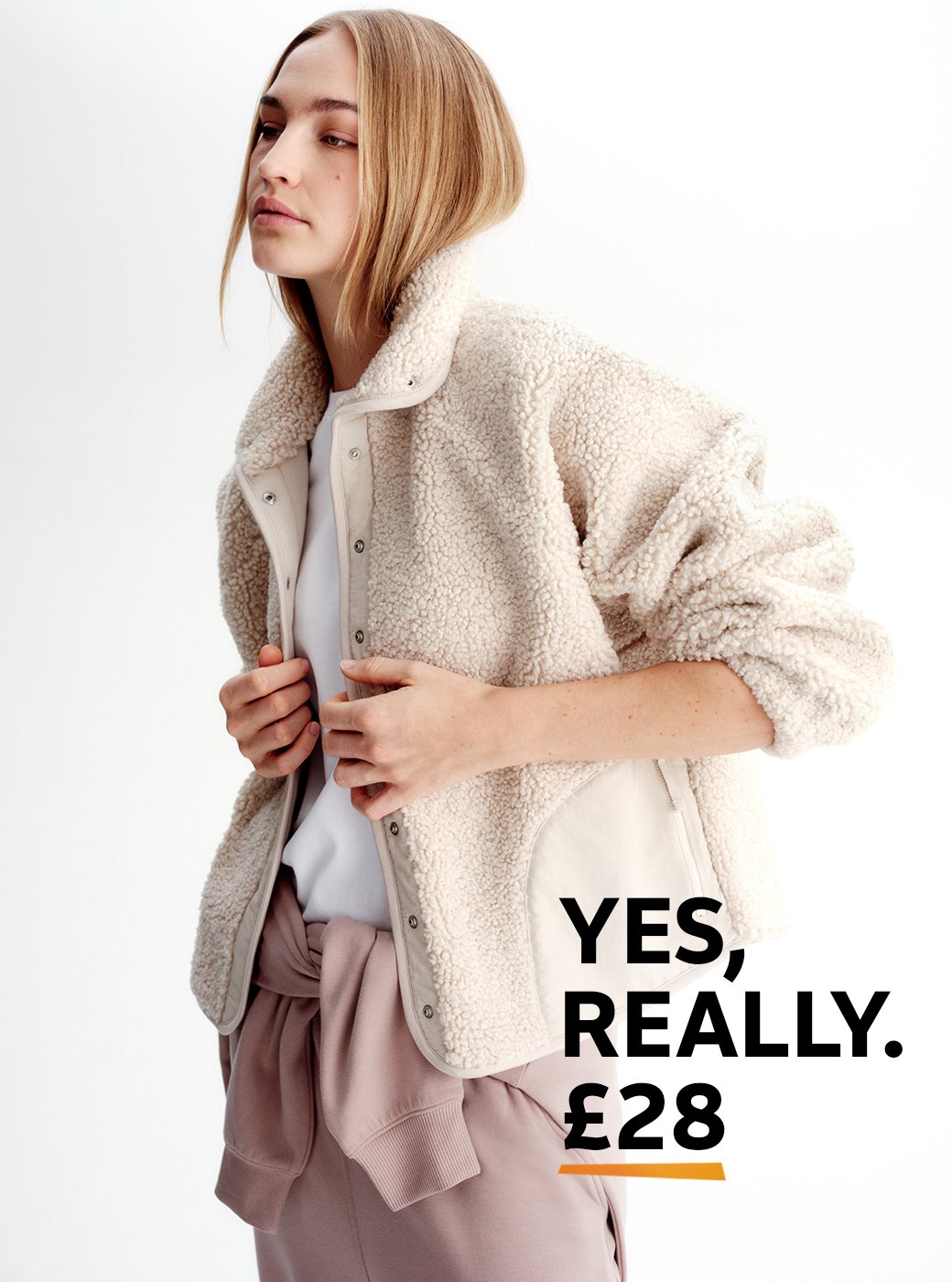 A woman wearing a soft borg jacket, with light pink jogging bottomsand a white t-shirt.