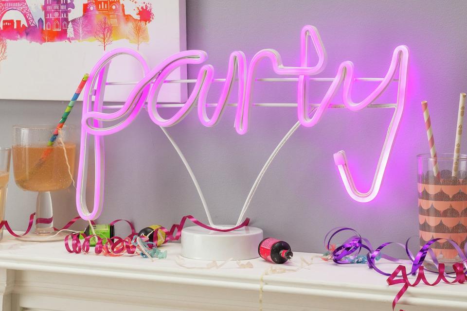 Neon pink party sign on mantlepiece.