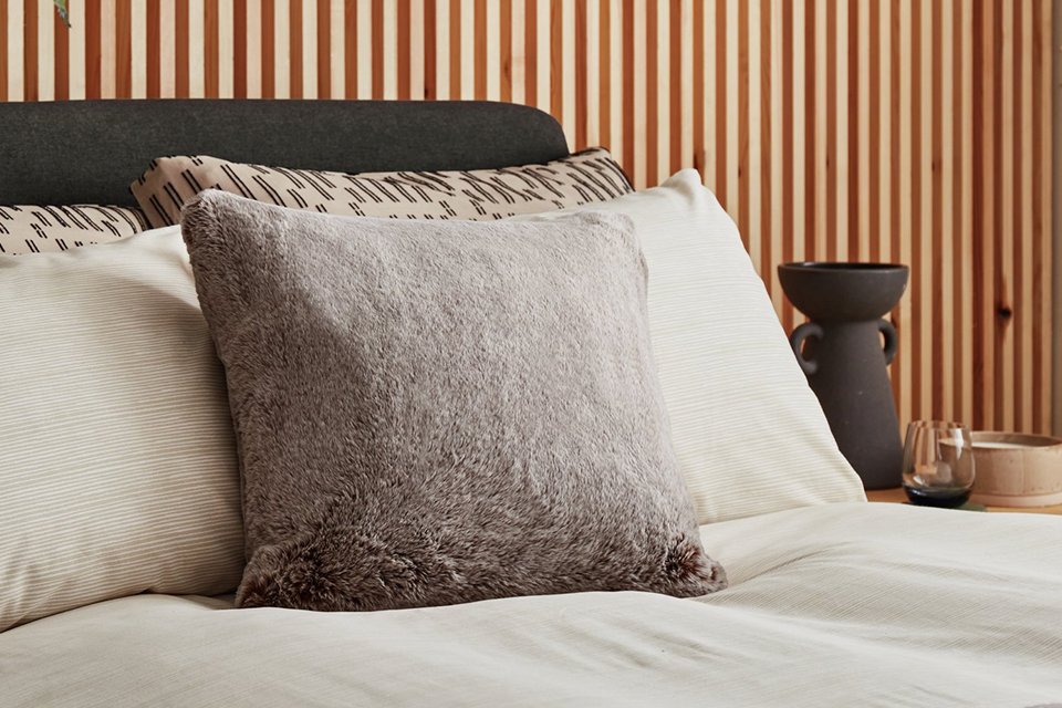 A cosy bed with pillows and cushions.