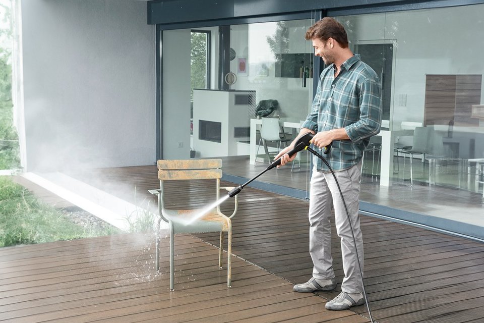 A man using a 1400W Karcher K2 Power Control Car & Home Pressure Washer to wash a patio chair.