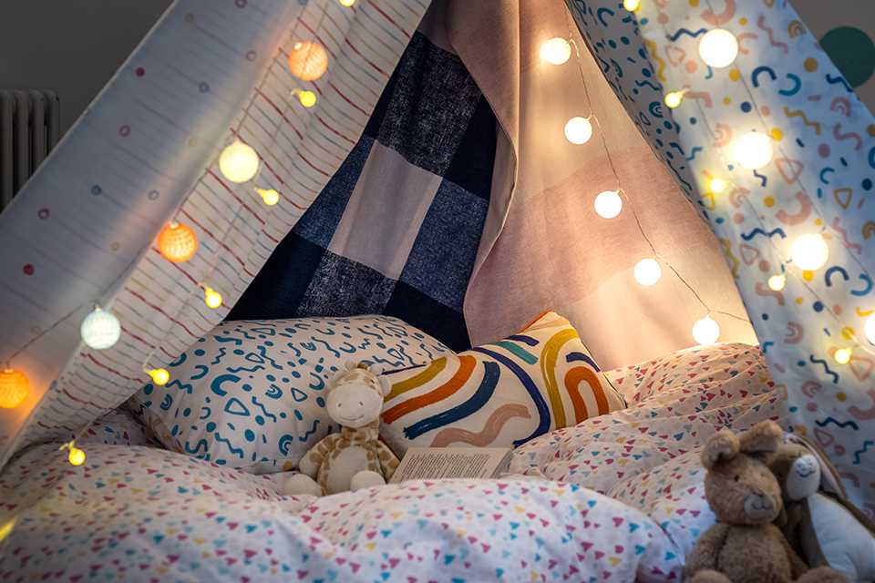 Children's bed with fairy lights and cushions.