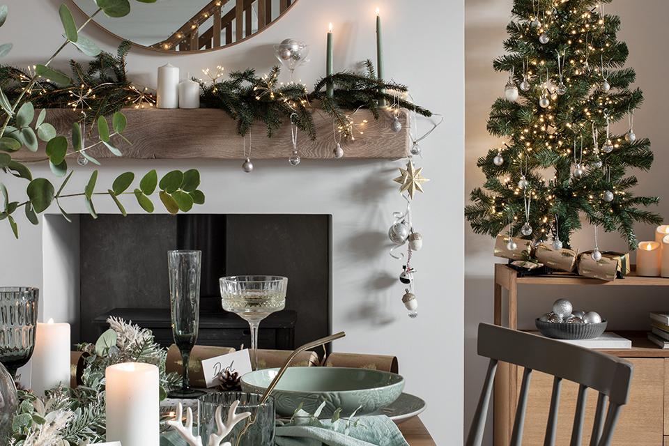 A dining table decorated with festive tableware sitting in front of the fireplace. 