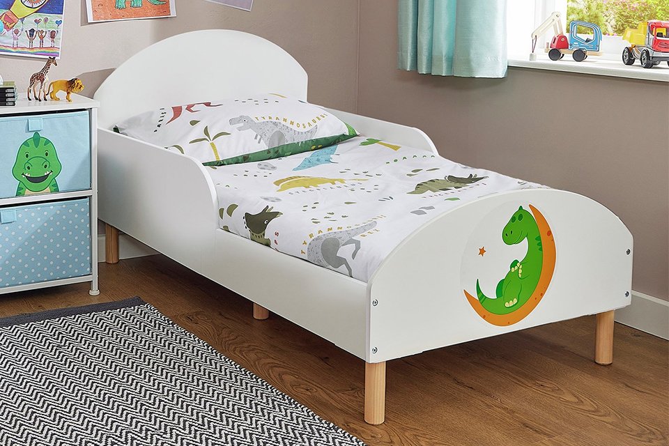 Liberty House Dinosaur Toddler Bed Frame in white colour placed in a kid's bedroom next to a window.