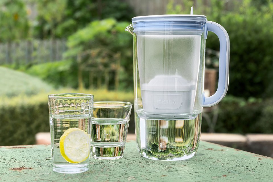 BRITA glass jug on a table next to two glasses of water.