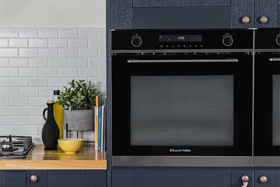 A black Russell Hobbs built-in oven in a blue kitchen.