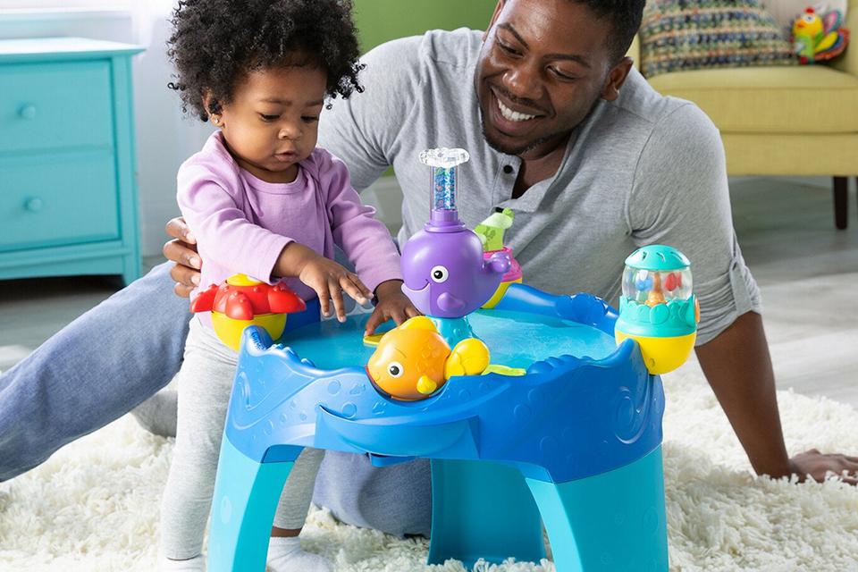Dad and daughter playing with a children's activity table.