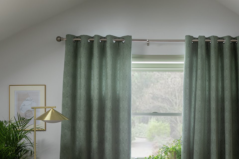 Habitat Geo Jacquard thermal eyelet curtains in green on a window.