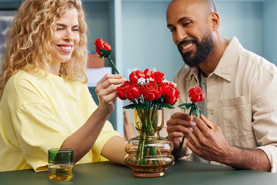 Man and woman putting LEGO® roses into a glass vase.