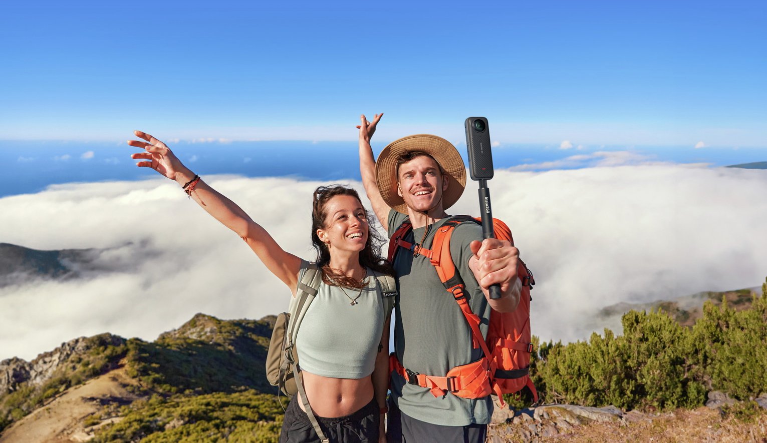 A couple using an Insta360 X4 Action camera to click a picture on the side of a cliff.