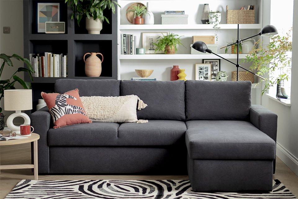 A dark grey sofa near a black and white rug in a living room.