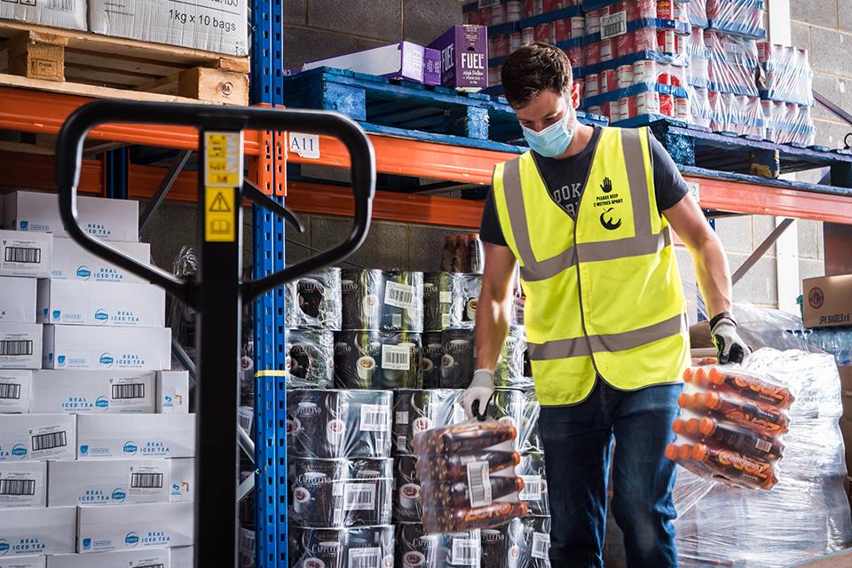 A man picking a pack of soft drinks in a warehouse.