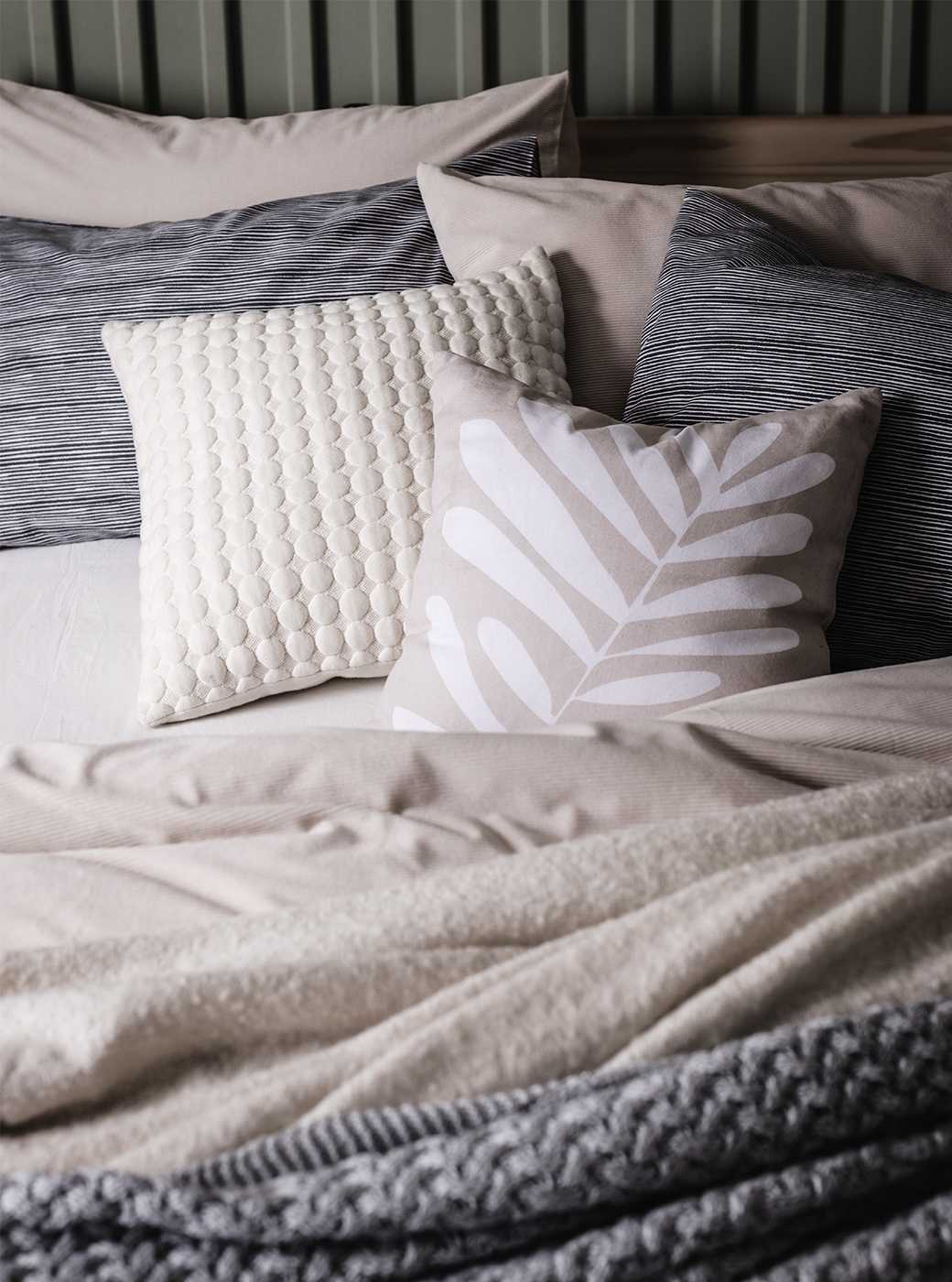Textured cushions in neutral colours on bed.