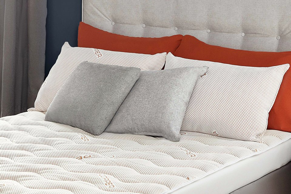 Six pillows on a neatly layered mattress topper on a bed.