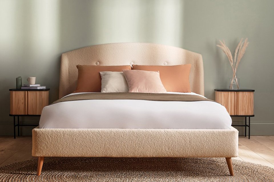 Green bedroom with cream boucle bed in bedroom.