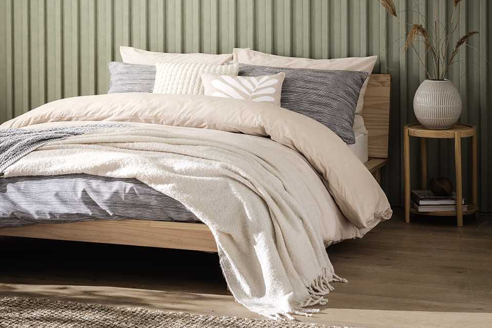 A bed layered with mattress, duvet, pillows and blankets.