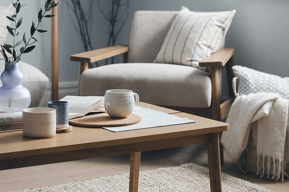 A rectangular coffee table against an armchair in a living room.