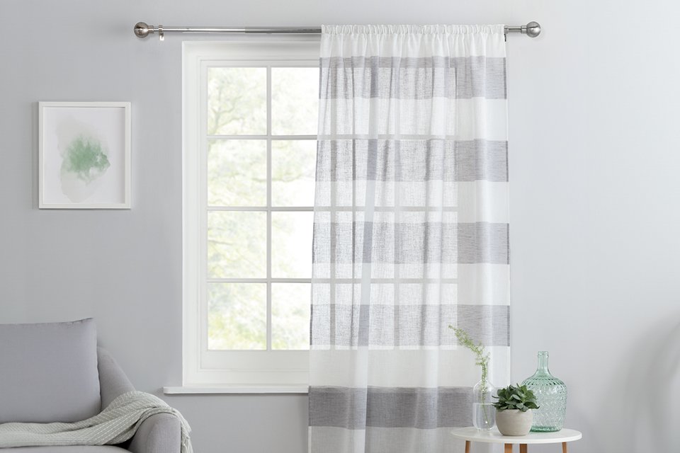 A Habitat grey and white striped linen pencil pleat sheer curtain on a window.