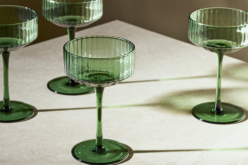 Champagne coupe in green colour placed on a dining table.