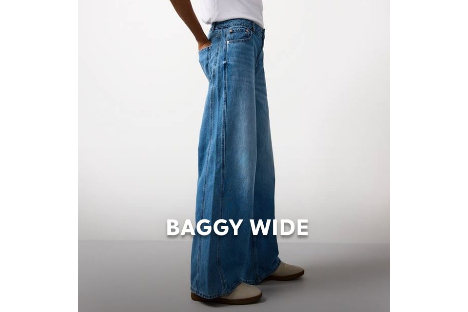 Model wearing wide‑leg baggy jeans in soft blue denim with a loose, relaxed fit. 