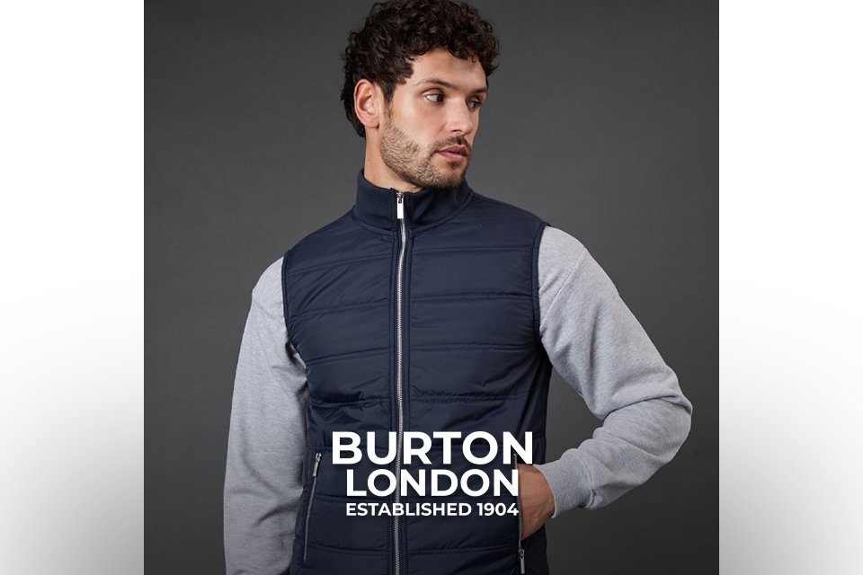 Navy padded zip‑up gilet layered over a grey sweatshirt and dark jeans. 