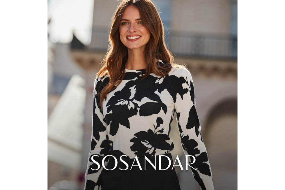 Black and white floral long‑sleeve top paired with high‑waisted black trousers.
