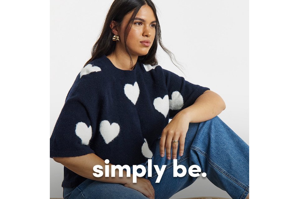 Navy short‑sleeve sweater with white heart pattern styled with relaxed blue jeans.