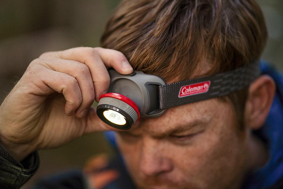 Man adjusting the head torch that is on his forehead.
