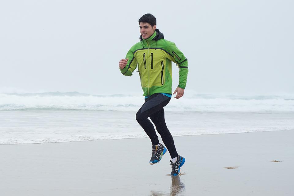 A man running on a beach in wet weather.