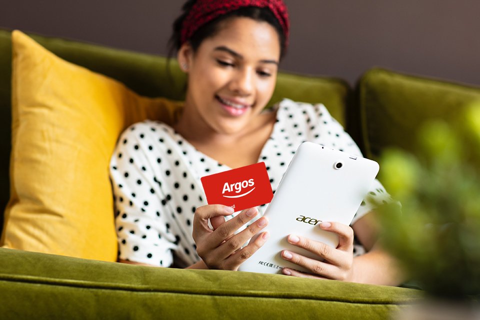 Woman holds argos gift card and a tablet in her hands.
