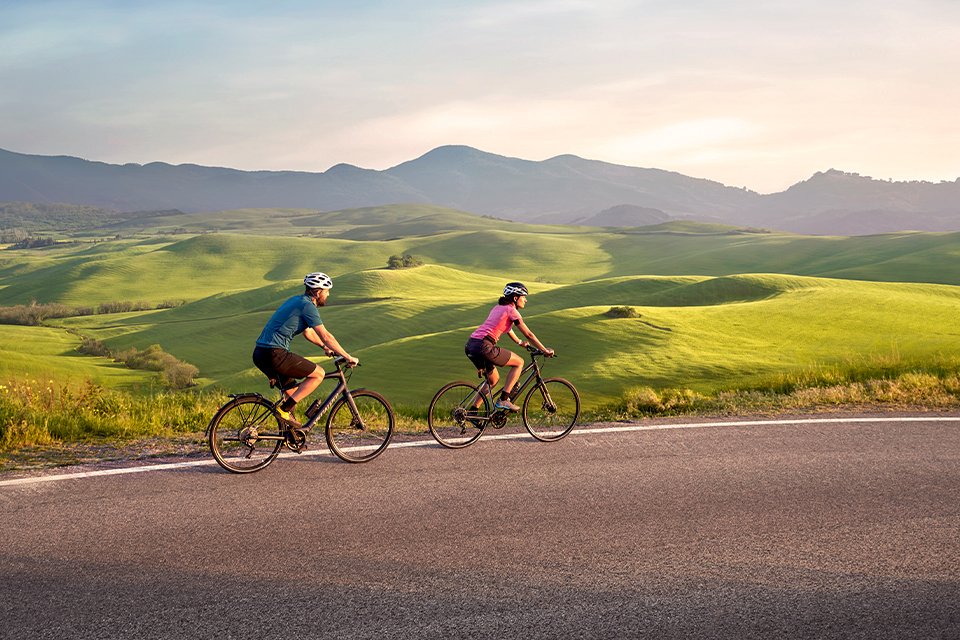 Two passing cyclists on their bikes equipped with Garmin Edge® and Varia™ cycling products.
