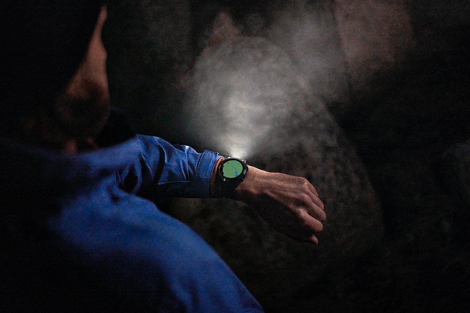  A man hiking in a cave creek using GPS and torch light on Garmin fēnix 7® Pro adventure smartwatch. 
