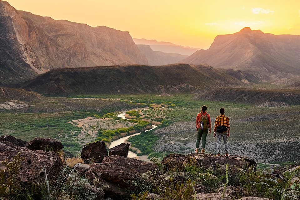 Two hikers on a viewpoint wearing GPS smartwatches from Garmin Instinct series.