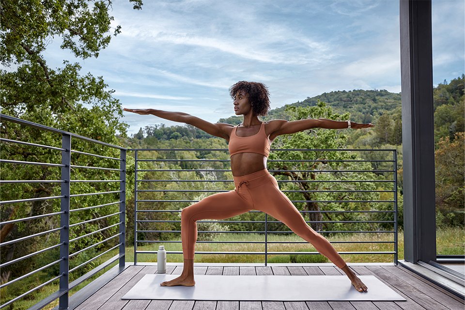 A woman doing warrior yoga pose wearing Garmin Venu® 3 GPS smartwatch.