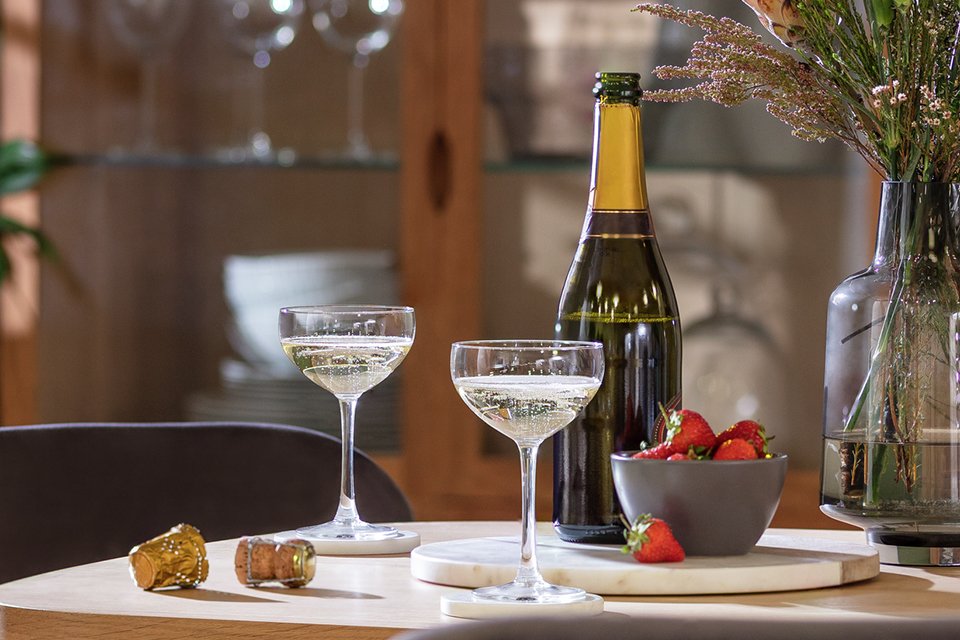 Habitat Portofino set of 2 champagne coupe glasses placed on a table next to a bottle of champagne.