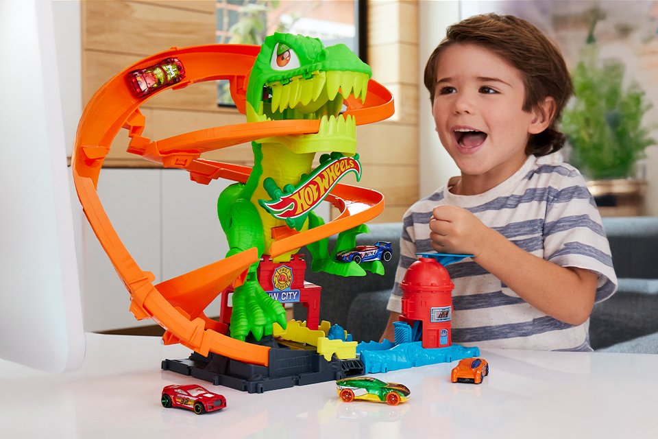 A kid playing with Hot Wheels City Car Track Set, T-Rex Blaze Battle Playset.