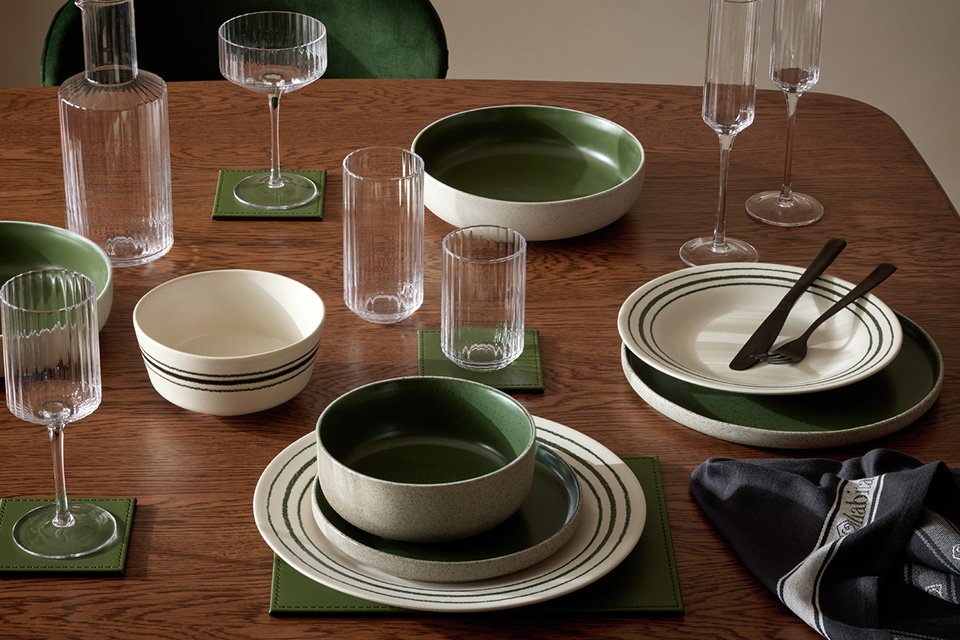 Habitat matte finish raw edge 12 piece dinner set in green and white on a wooden dining table. 