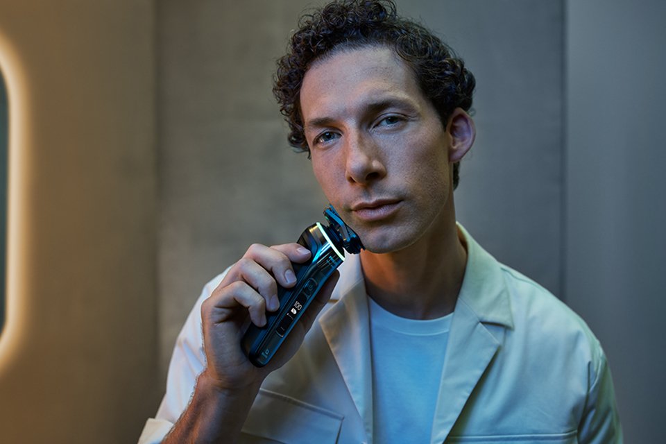 A man holding a Philips shaver against his clean-shaven face.